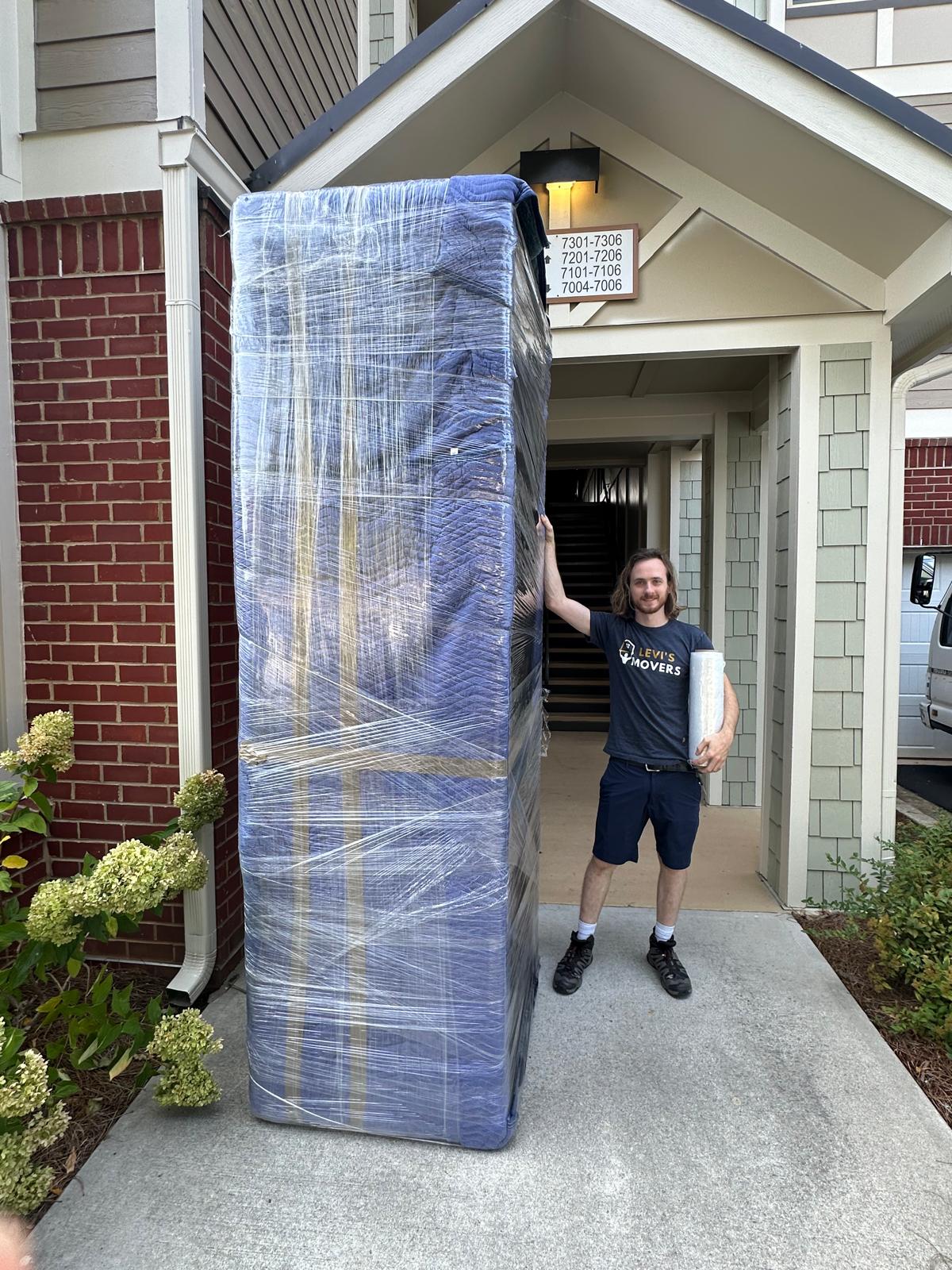 Mover carrying wrapped furniture out of an apartment building