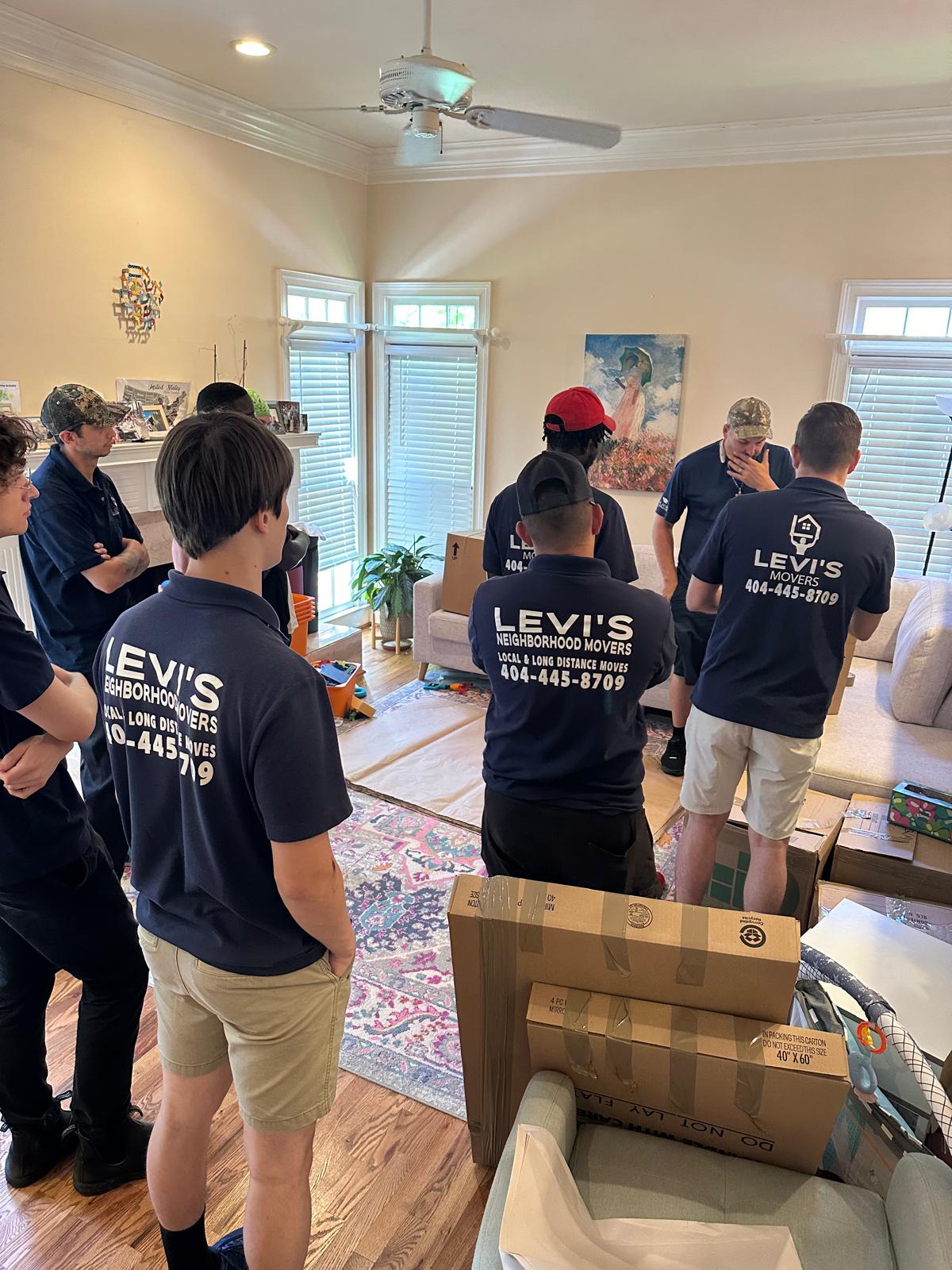 Levi's Movers crew packing boxes and furniture inside a client's living room