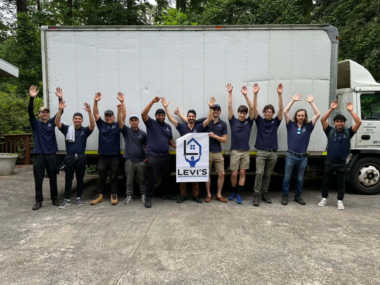 Levi's Movers crew in front of their truck holding a company sign